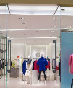 Μανεκέν με γυναικεία πανωφόρια σε μπλε και ροζ, αναδεικνύουν στυλάτες επιλογές σε βιτρίνα κατάστημα.