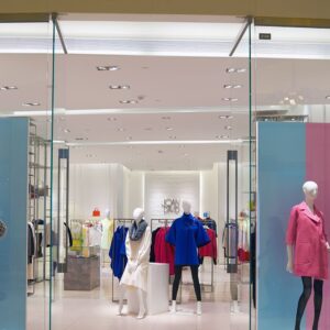 Γυναικείες καμπαρντίνες σε βιτρίνα καταστήματος, πολύχρωμα σχέδια, φθινοπωρινή μόδα.