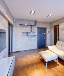 Καθιστικό με μοντέρνο κρεμ καναπέ, κομψά ράφια και μίνιμαλ διακόσμηση σε ζεστή απόχρωση ξύλου.