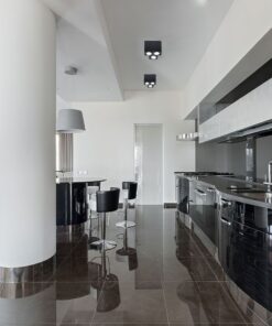 Μοντέρνα μαύρη κουζίνα με γυαλιστερά ντουλάπια, υψηλές καρέκλες και ενσωματωμένο φωτισμό οροφής.