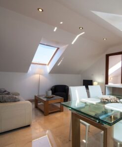 Καθιστικό σοφίτας με λευκό καναπέ, τραπέζι από γυαλί και ξύλο, πολυθρόνα, φωτεινό ανοίγοντας παράθυρο.