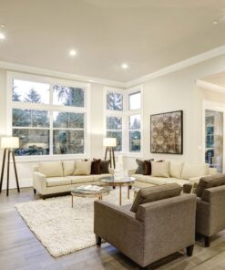 Σαλόνι με μοντέρνα έπιπλα, δύο λευκούς καναπέδες, γκρι πολυθρόνες και φωτιστικά δαπέδου, ιδανικό για άνεση.