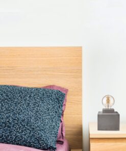 Κομψή κρεβατοκάμαρα με ξύλινο κεφαλάρι, μπλε μαξιλάρι και μοντέρνο φωτιστικό στο κομοδίνο.