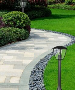 Πλακόστρωτο μονοπάτι με φωτισμό κήπου, περιτριγυρισμένο από πράσινο γρασίδι και θάμνους.