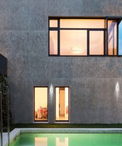 Σύγχρονη κατοικία με φωτισμένα παράθυρα και πισίνα στο εξωτερικό, το σούρουπο.